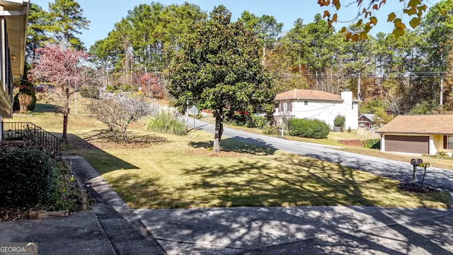 a view of a house with a yard and large tree
