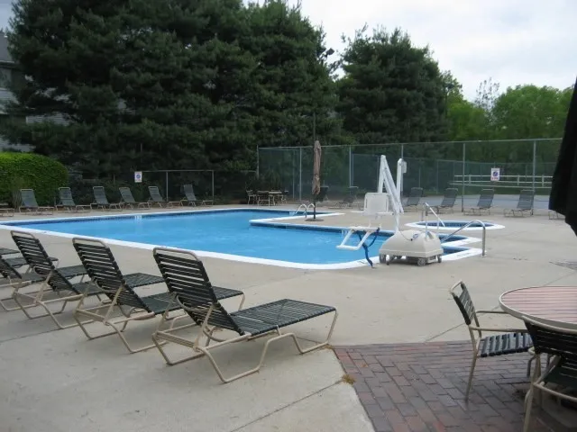 a view of swimming pool with chairs and wooden fence