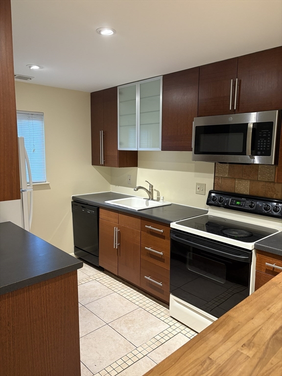 24 Silver Hill Lane, Unit 24 Natick, MA 01760 - Photo 3 of 15 a kitchen with kitchen island granite countertop stainless steel appliances and wooden cabinets