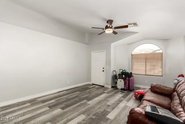 an empty room with windows and ceiling fan