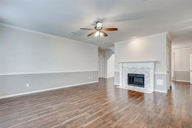 a view of an empty room with wooden floor fireplace and a window