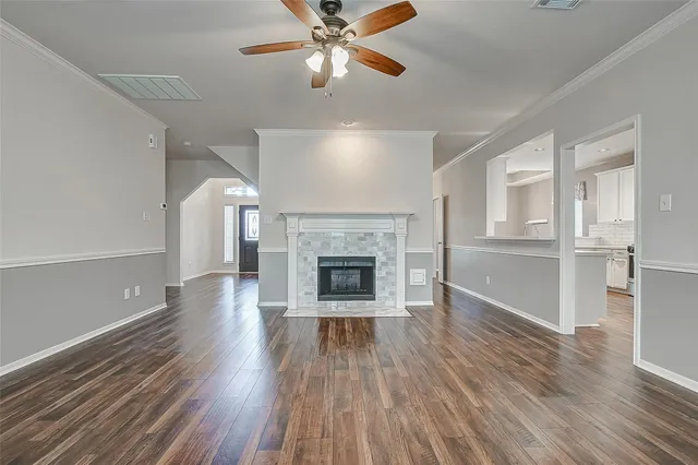 a view of a livingroom with wooden floor a ceiling fan and windows