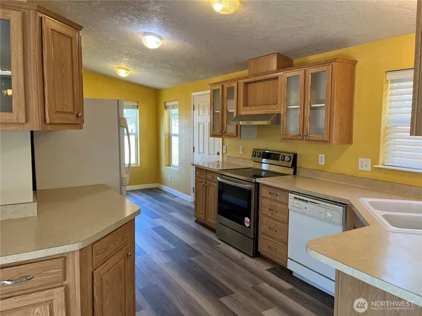 a kitchen with refrigerator and wooden floor