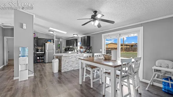 a kitchen with stainless steel appliances kitchen island granite countertop a refrigerator a stove a dining table and chairs with wooden floor