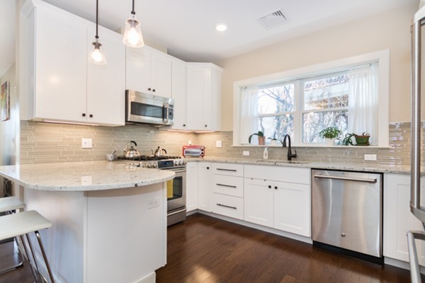 a kitchen with granite countertop white cabinets white appliances a sink and a large window