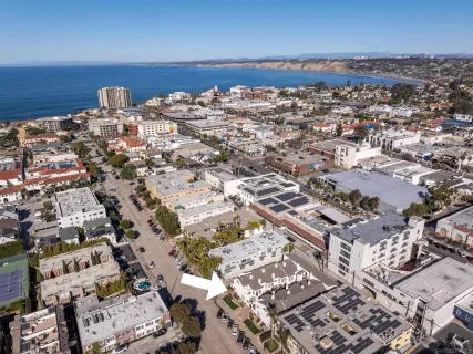 an aerial view of a city with ocean view in back