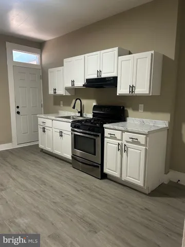 a kitchen with stainless steel appliances granite countertop a stove a sink and white cabinets