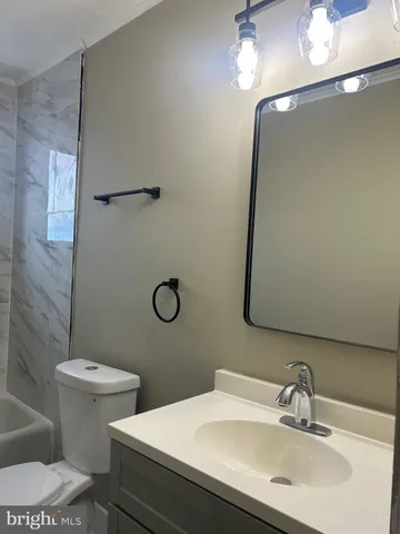 a bathroom with a sink a toilet a mirror and shower