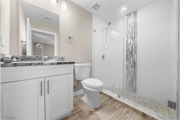 a bathroom with a granite countertop toilet sink and mirror