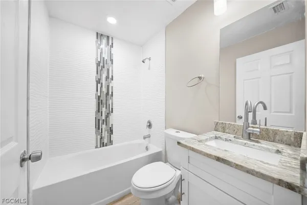 a bathroom with a granite countertop sink toilet a large mirror a shower and a bathtub