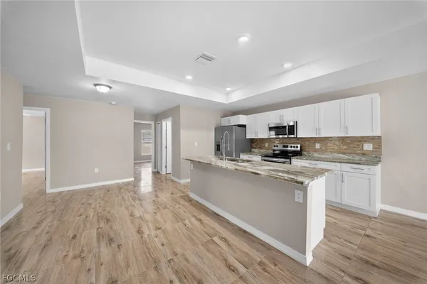 a kitchen with stainless steel appliances granite countertop a refrigerator a stove top oven a sink and dishwasher with wooden floor