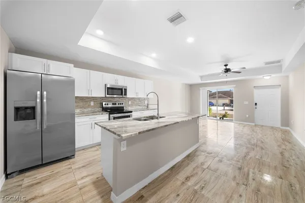 a large kitchen with kitchen island a sink stainless steel appliances and cabinets