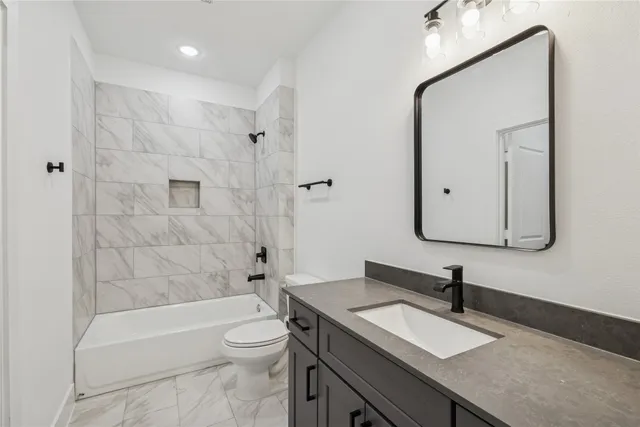 a bathroom with a granite countertop sink toilet a mirror and bathtub