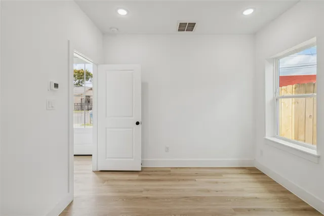 an empty room with wooden floor and windows