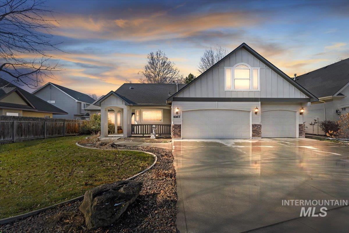 View of front facade with board and batten siding, concrete driveway, stone siding, and a porch