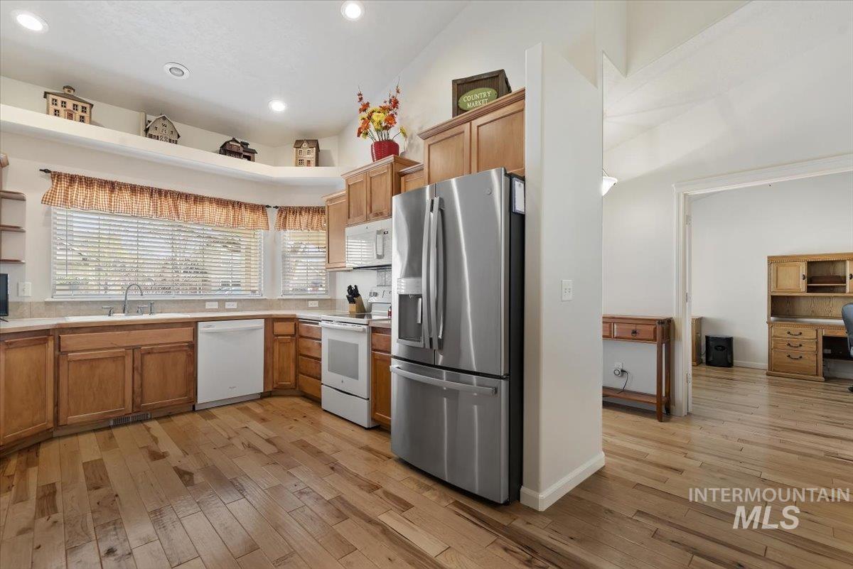 4167 North Arches Way Meridian, ID 83646 - Photo 11 of 36 Kitchen with white appliances, light wood-style flooring, light countertops, brown cabinets, and recessed lighting