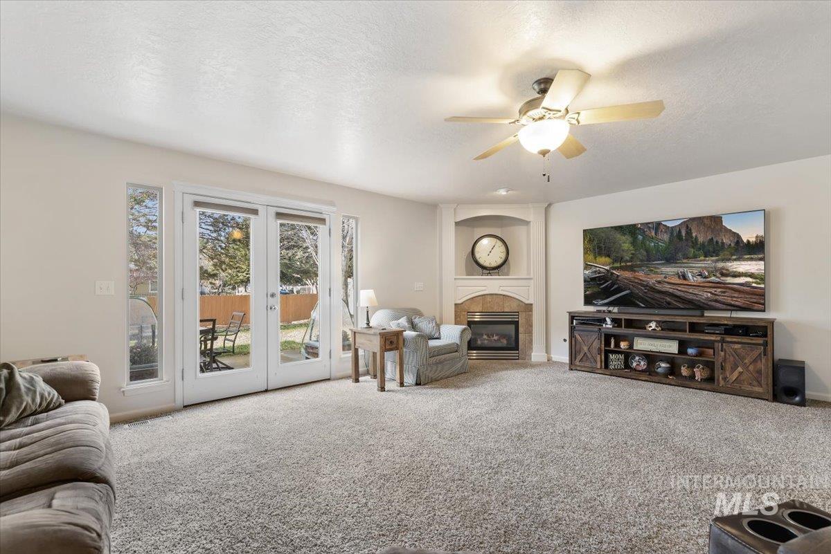 4167 North Arches Way Meridian, ID 83646 - Photo 8 of 36 Carpeted living room featuring a large fireplace, french doors, a ceiling fan, and a textured ceiling
