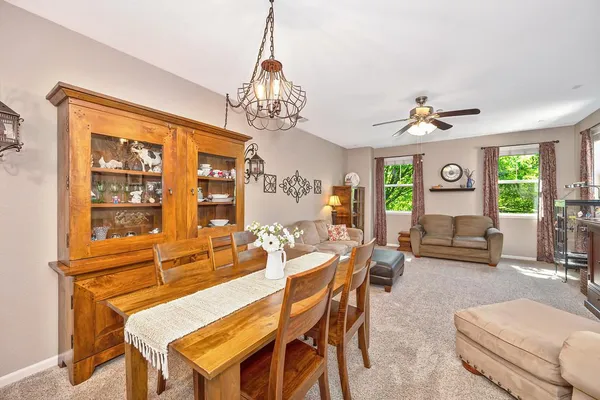a view of a dining room with furniture a chandelier and large windows