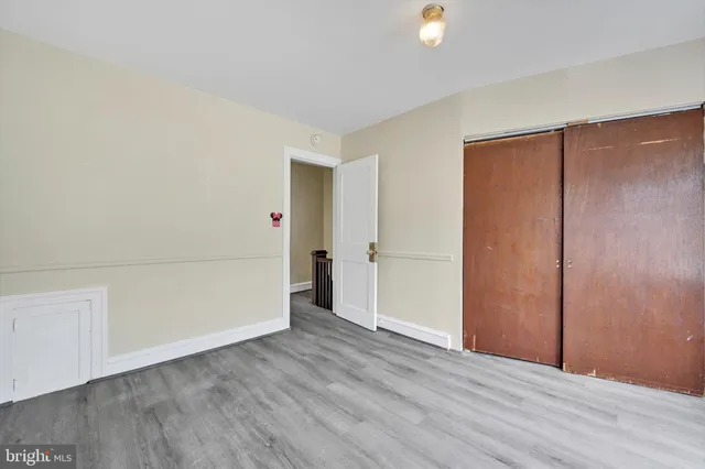 a view of an empty room with wooden floor and closet