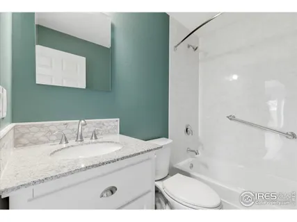 a bathroom with a granite countertop sink a mirror and a bathtub