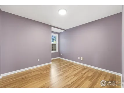 a view of an empty room with window and wooden floor