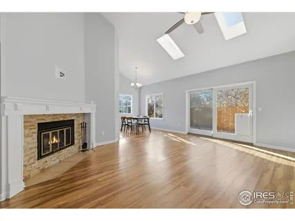 a view of an empty room with wooden floor and a fireplace