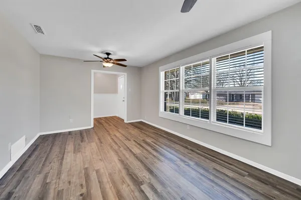a view of an empty room with a window and wooden floor