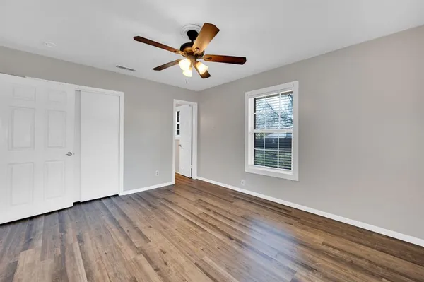 a view of an empty room with wooden floor and a window