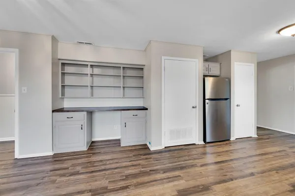 an empty room with wooden floor and cabinet