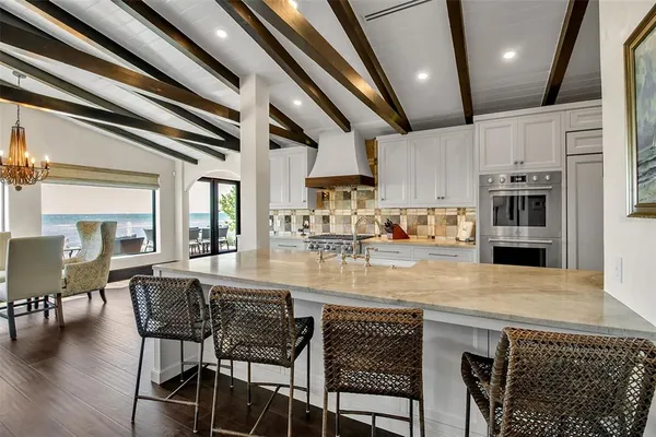 a kitchen with stainless steel appliances kitchen island granite countertop a table chairs sink and cabinets