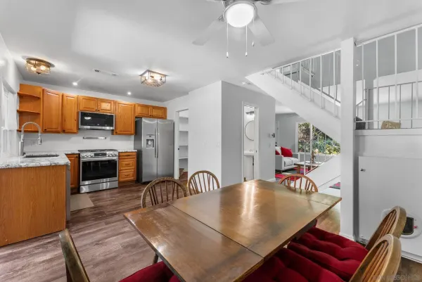 a kitchen with stainless steel appliances granite countertop a stove a sink dishwasher a dining table and chairs with wooden floor