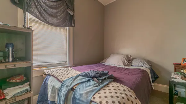 a bedroom with a bed and a lamp on the dresser