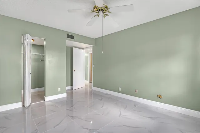 an empty room with a chandelier fan and entryway
