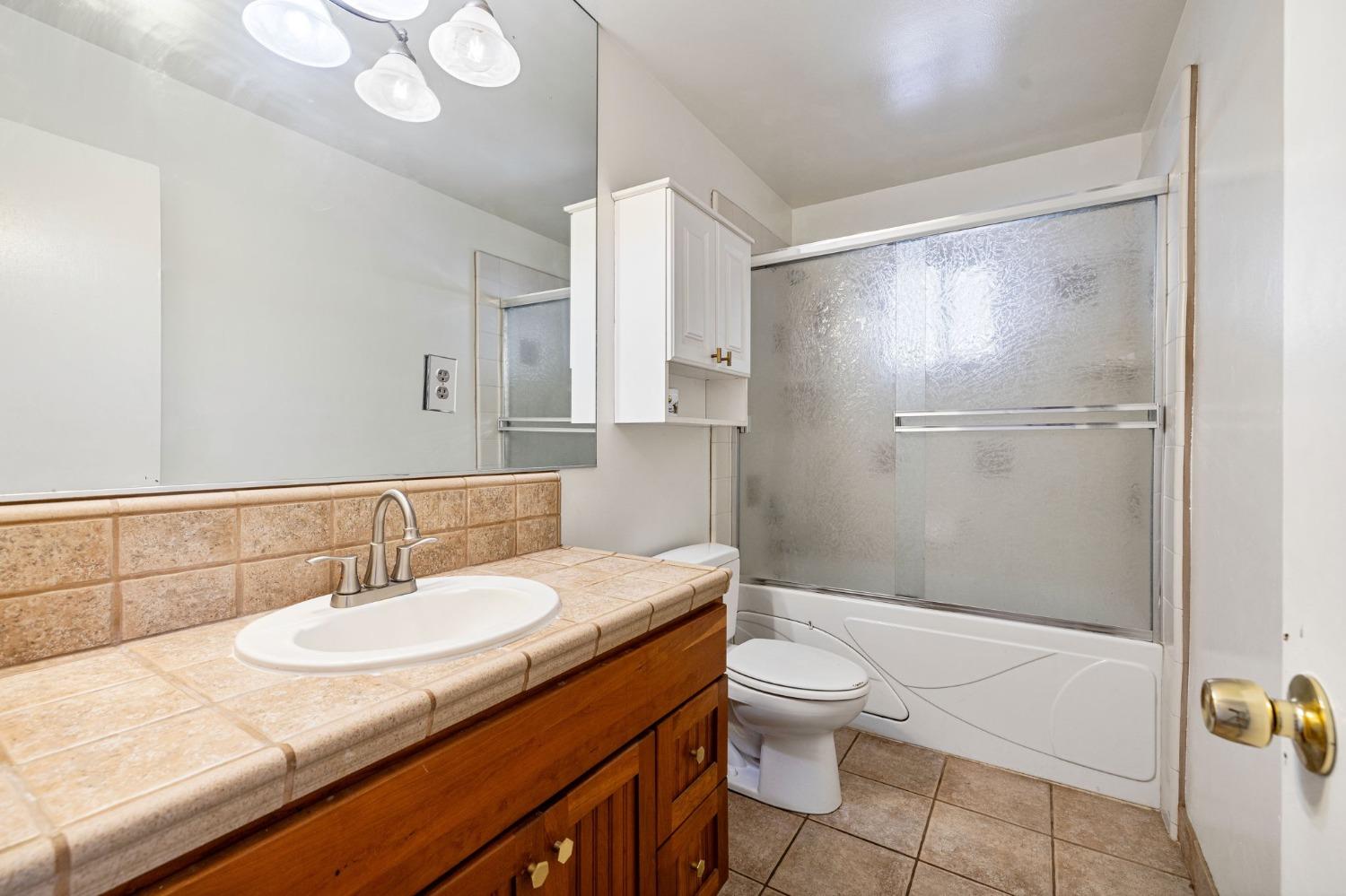 1345 Peach Avenue Clovis, CA 93612 - Photo 16 of 27 a bathroom with a shower sink vanity mirror and toilet