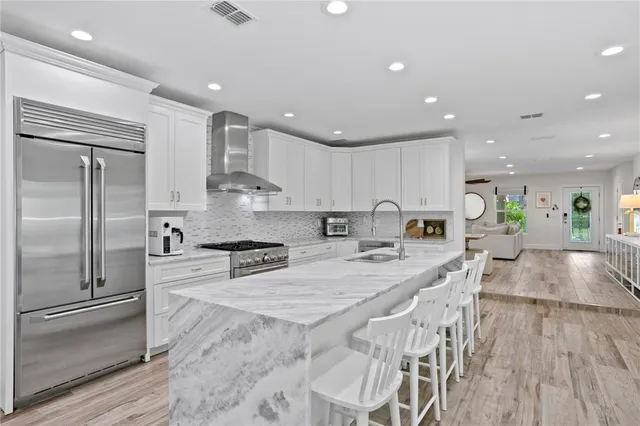 a large kitchen with kitchen island a dining table chairs and white cabinets
