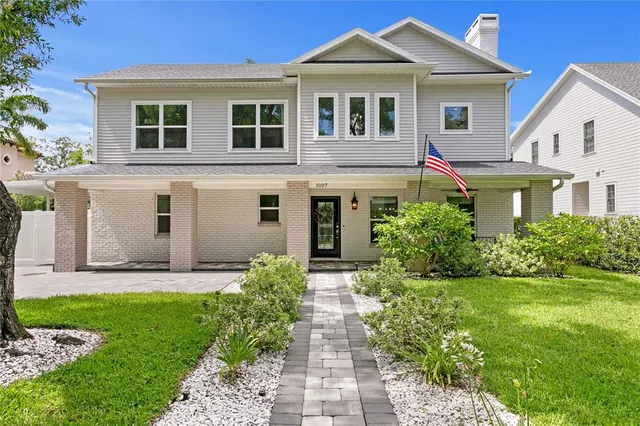 a front view of a house with a yard and potted plants