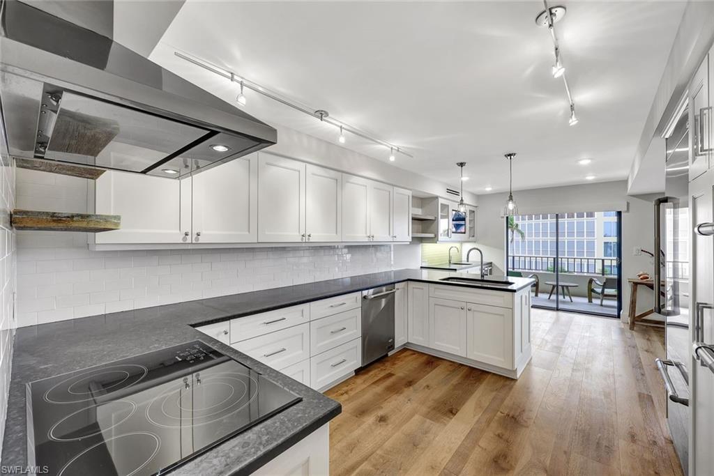 4451 Gulf Shore Boulevard North, Unit 506 Naples, FL 34103 - Photo 4 of 32 a kitchen with stainless steel appliances granite countertop a sink dishwasher a stove and white cabinets with wooden floor