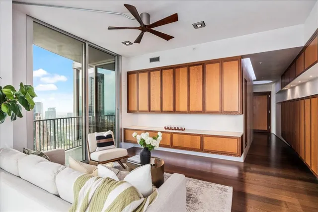 a living room with furniture a ceiling fan and a large window