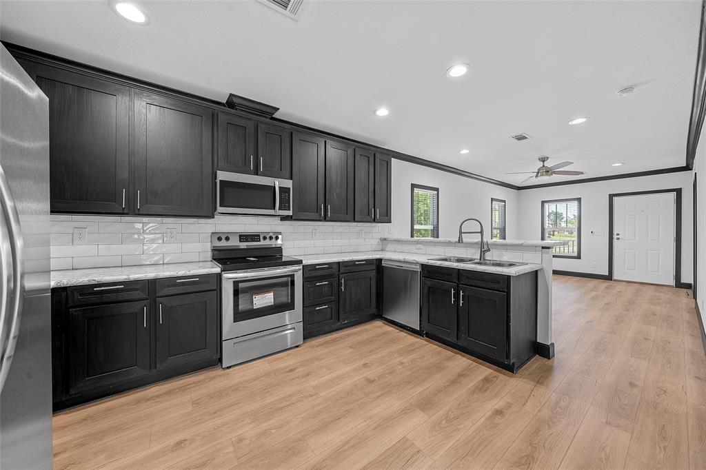 a kitchen with stainless steel appliances kitchen island granite countertop a stove top oven and sink