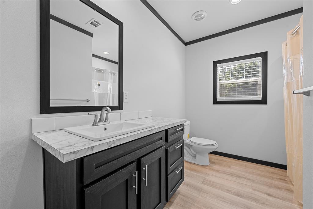 202 6th Street Mount Calm, TX 76673 - Photo 14 of 23 a bathroom with a granite countertop sink mirror and toilet