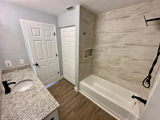 a bathroom with a granite countertop sink a mirror and shower