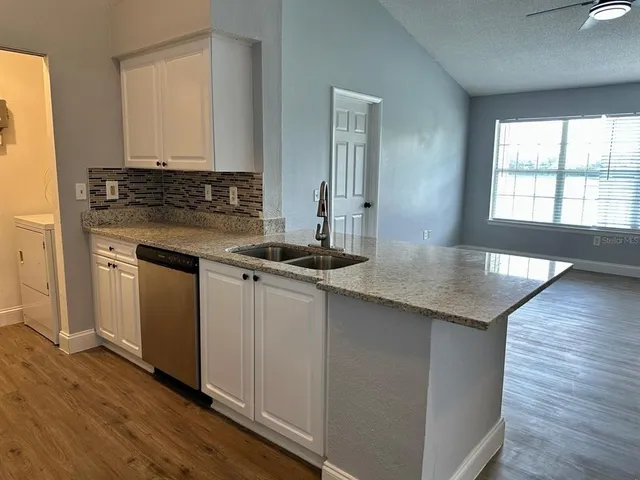 a kitchen with granite countertop a sink cabinets and wooden floor
