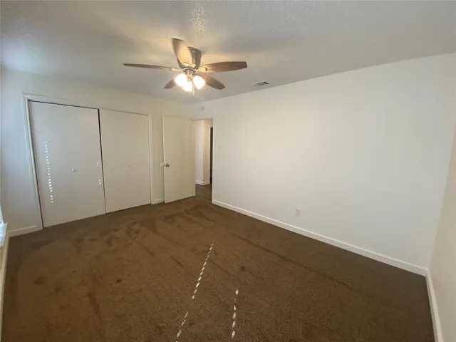 an empty room with a window and a fan