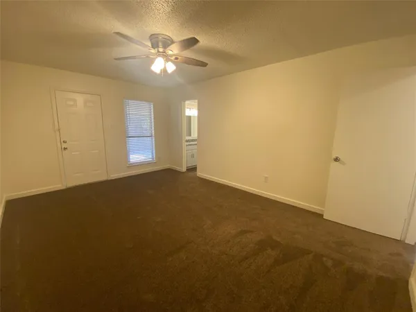 an empty room with a chandelier fan and windows