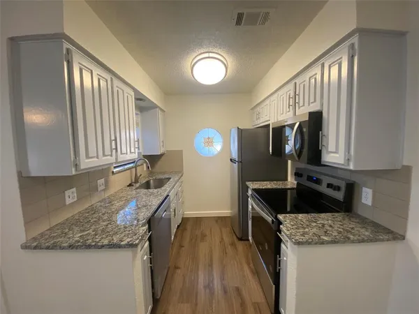 a kitchen with granite countertop a sink a counter top space appliances and cabinets