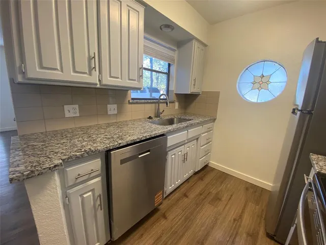 a kitchen with cabinets appliances and a wooden floor