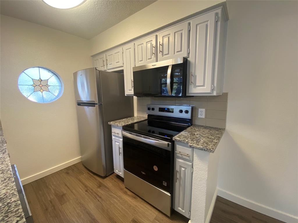 3108 Timber Ridge Point Grapevine, TX 76051 - Photo 7 of 16 a kitchen with stainless steel appliances granite countertop a stove a microwave and a refrigerator