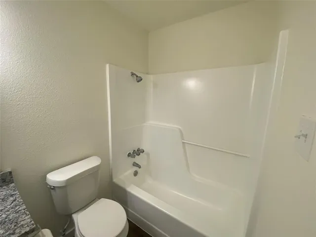 a white toilet sitting next to a bath tub