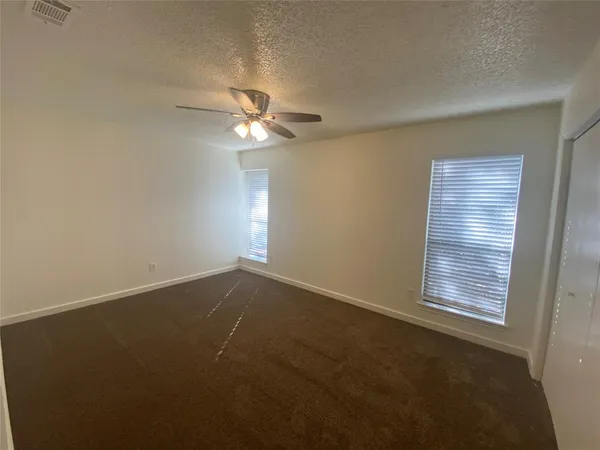 an empty room with windows and fan