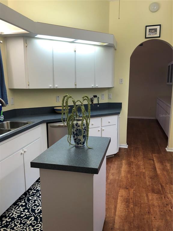 7867 Southwest 115th Loop Ocala, FL 34476 - Photo 11 of 40 a kitchen with kitchen island granite countertop a sink a stove cabinets and wooden floor